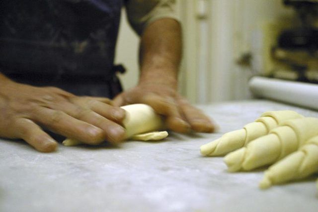 Un boulanger handrolling croissants sur une surface de travail.