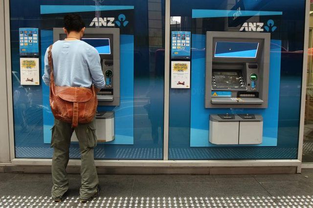 Un homme sur le trottoir en utilisant une machine bancaire ATM