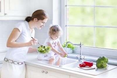 Fille et sa mère se laver les légumes dans un évier de cuisine