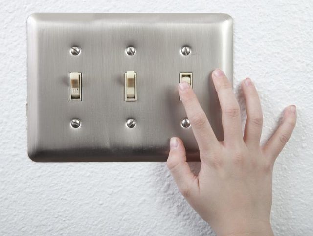 Jeune garçon's hand turning on a light switch.