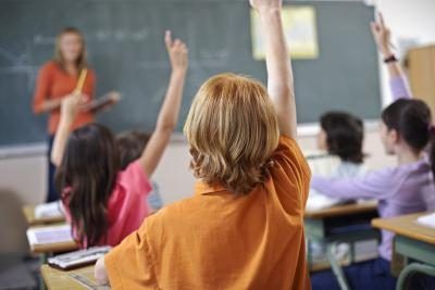 Es élèves attentifs élèvent leurs mains dans une salle de classe.
