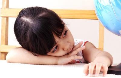 Une petite fille pose sa tête sur son bras à son bureau.