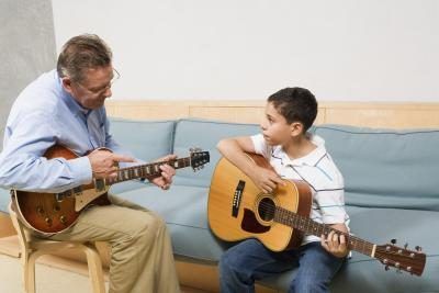 Instructeur enseignant jeune garçon à jouer de la guitare.