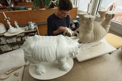 Un artiste fait une statue de porcelaine d'un rhinocéros.