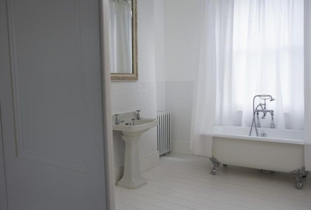 Une douche rideau blanc pure autour d'une baignoire sur pattes.