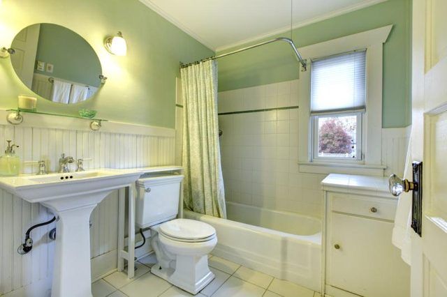 Blanc carrelage, lambris et des accessoires dans une salle de bains vert pâle.