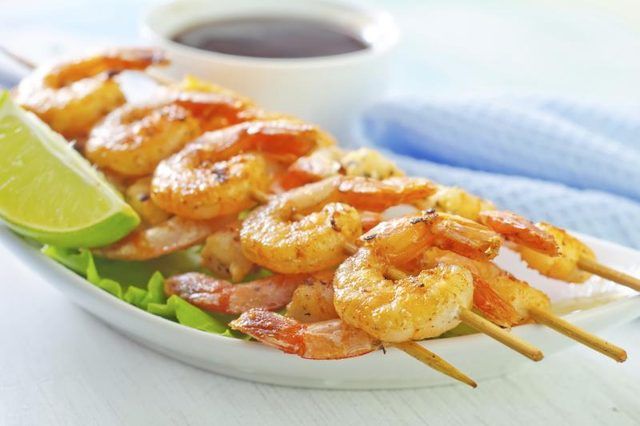 Crevettes grillées sur des brochettes avec de la chaux et de sauce.