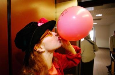 Femme soufflant jusqu'à ballon rose