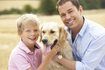 Un jeune garçon et son père caresser leur golden retriever.