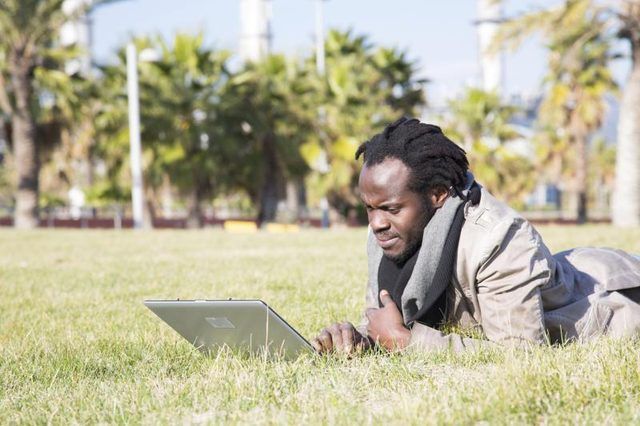 Un étudiant utilise son ordinateur portable à l'extérieur.