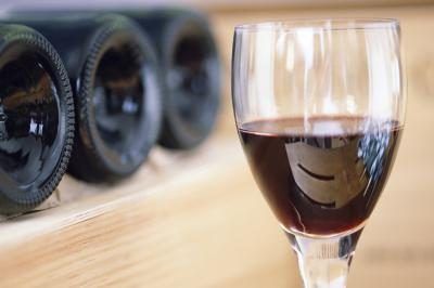 Un verre de vin rouge avec des bouteilles en arrière-plan