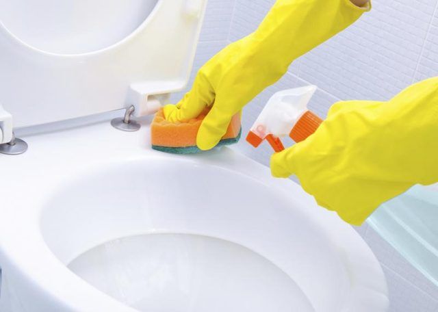 Close-up de deux mains gantées nettoyage des toilettes