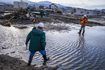 Deux experts à pied dans l'eau à un site détruit par un tremblement de terre.