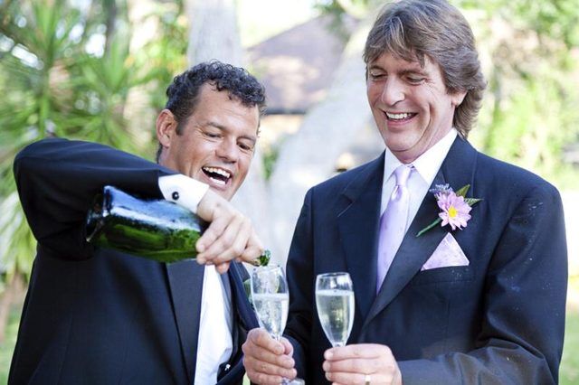 Un couple gay se déverse champagne pour célébrer leur mariage.