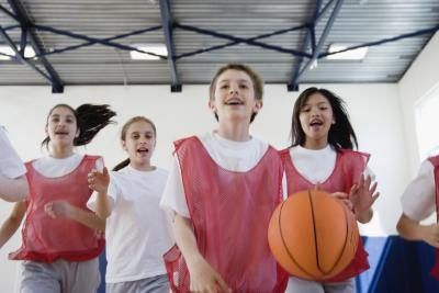 Un groupe d'étudiants jouer au basket dans un gymnase de l'école.