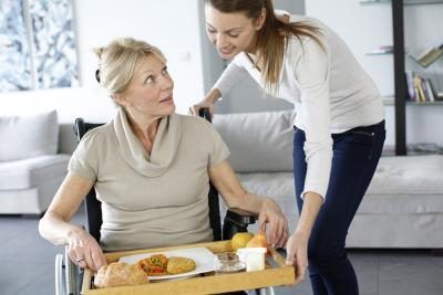 Une aide de soins à domicile aide son patient avec son repas.