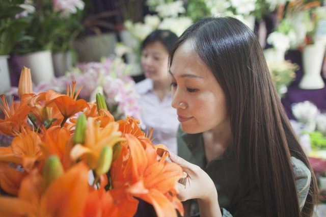 Femme sentant un bouquet de fleurs d'orange dans un magasin.
