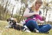 Mère allaitant son bébé à côté de leur chien dans un parc.