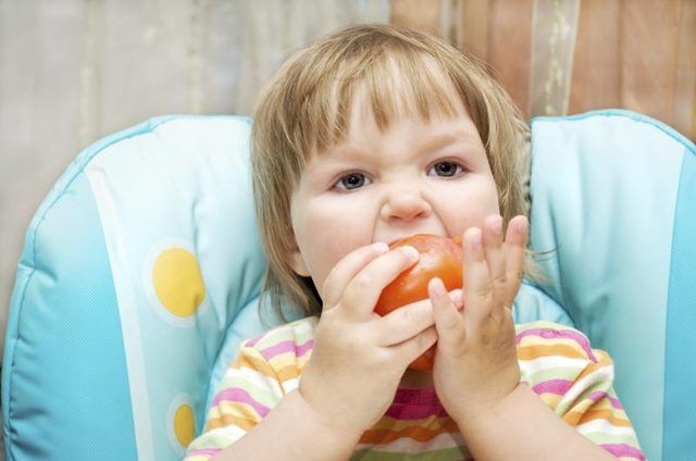 Toddler manger une tomate fraîche.