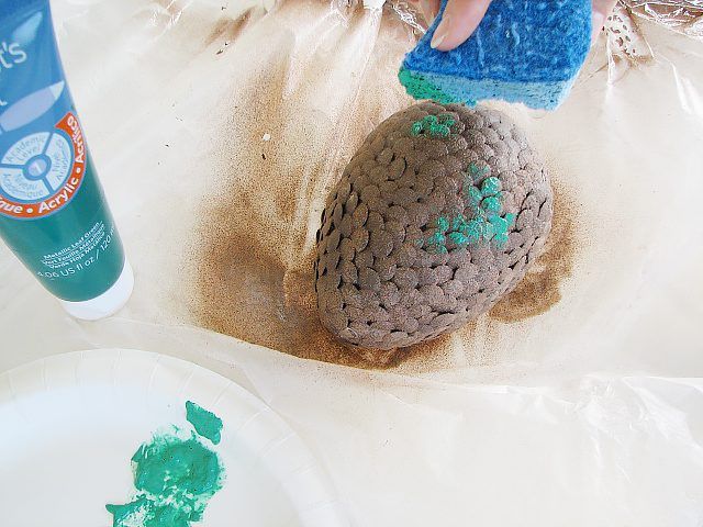 Sponge peindre un peu de peinture d'artisanat bleu-vert sur la finition de la rouille.