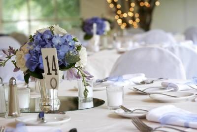 Fleurs bleues royales sont sur le centre de tables de réception blancs.