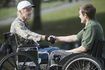 Jeune homme en fauteuil roulant en secouant la main du vétéran en fauteuil roulant.