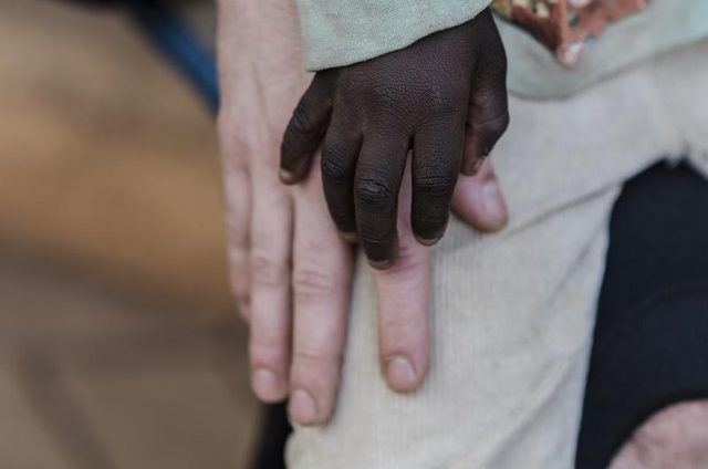 Une main d'un jeune garçon afro-américaine tient la main d'un homme de race blanche âgé