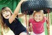Deux jeunes filles, jouant sur une balançoire ensemble à une aire de jeux.