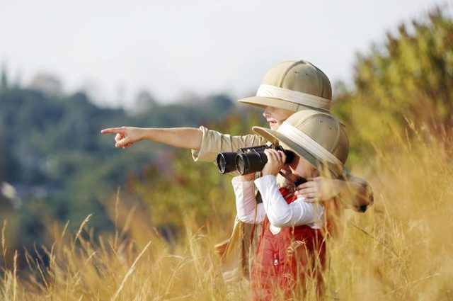 Garçon et fille avec chapeau safari avec des jumelles.