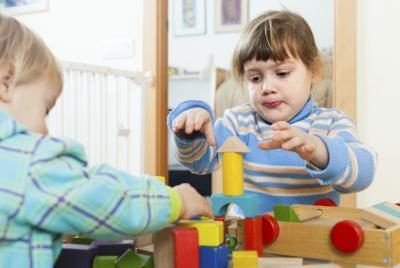 Deux bambins jouant avec des blocs de construction à une table.
