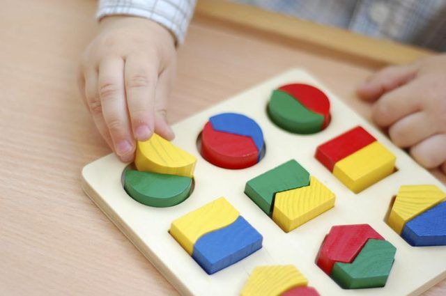 Un bambin de jouer avec un puzzle coloré formes.