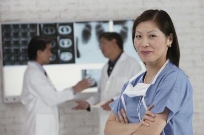 Un assistant médical femme debout en face de deux médecins regardant des épreuves de X-ray.