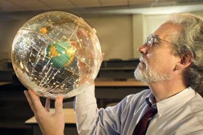 Professeur tenant un globe astronomique.