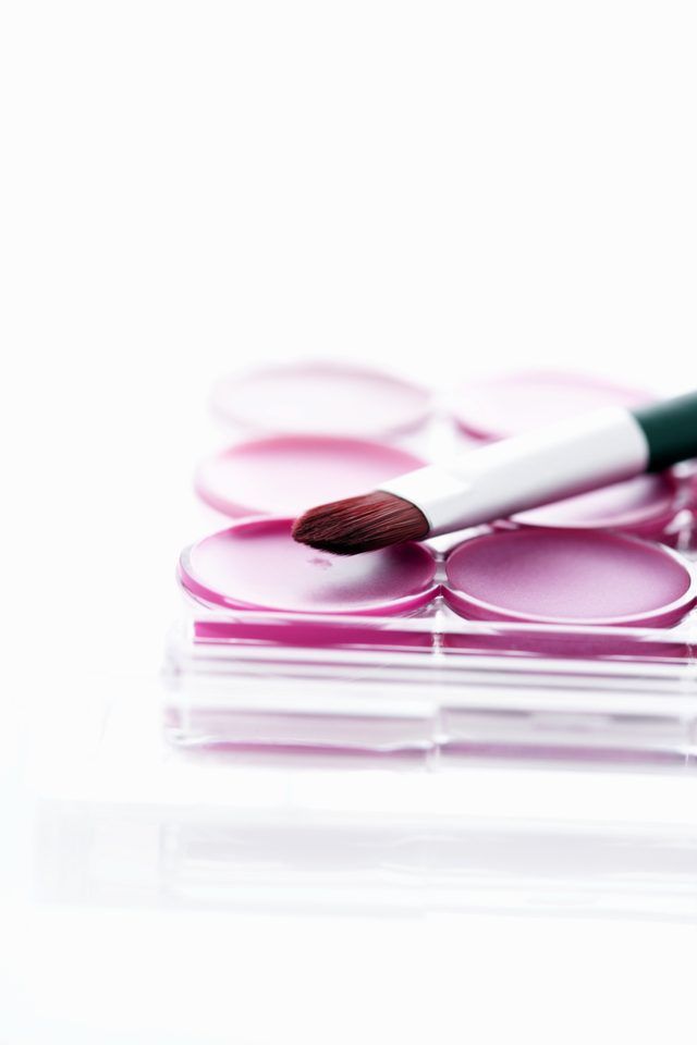 Un pinceau de maquillage sur le dessus d'une palette de rose.