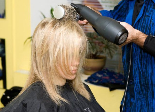 Une femme dans un salon devient son coup de cheveux séché.