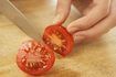 Close-up de la tomate étant tranché sur une planche à découper.