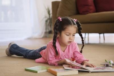 Jeune enfant lisant un livre sur le plancher
