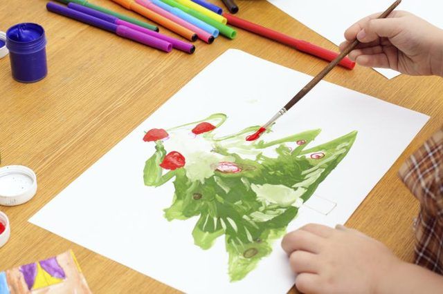 Un enfant d'âge préscolaire peint un arbre de Noël.