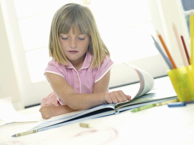 Une jeune fille est en feuilletant un livre de coloriage.