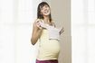 femme enceinte tenant les vêtements de bébé