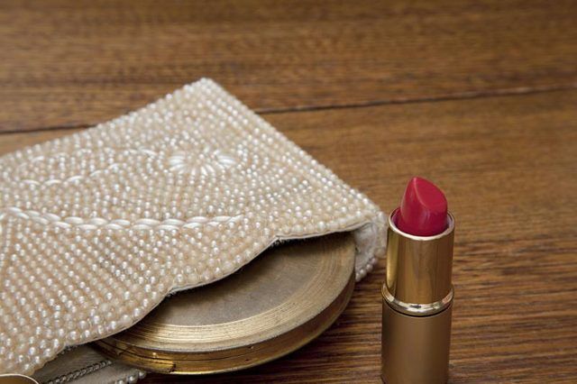 Un sac à main, miroir et rouge à lèvres de les années 1920 sur une table.