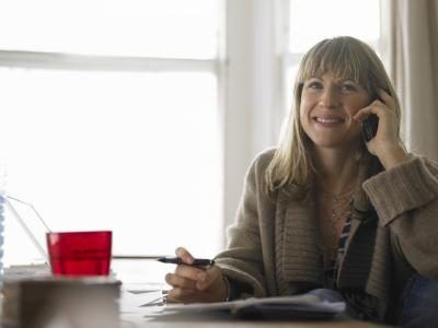 Une femme parle au téléphone dans son bureau à domicile.
