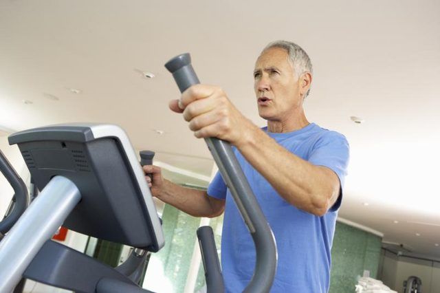 Un homme d'âge mûr utilise la machine elliptique à la gym.