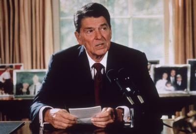 Le président Ronald Reagan assis à son bureau dans le bureau ovale, vers 1985