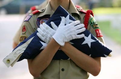 Une Eagle Scout tenant un drapeau bien plié.