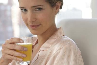 Une femme tenant un verre de jus d'orange.