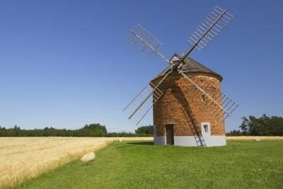 Un moulin à vent sur une ferme à côté d'un champ de blé.