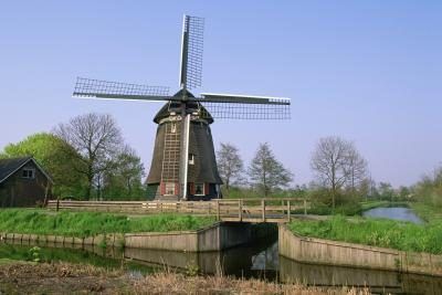 Un moulin à vent à côté d'un canal dans un paysage hollandais.