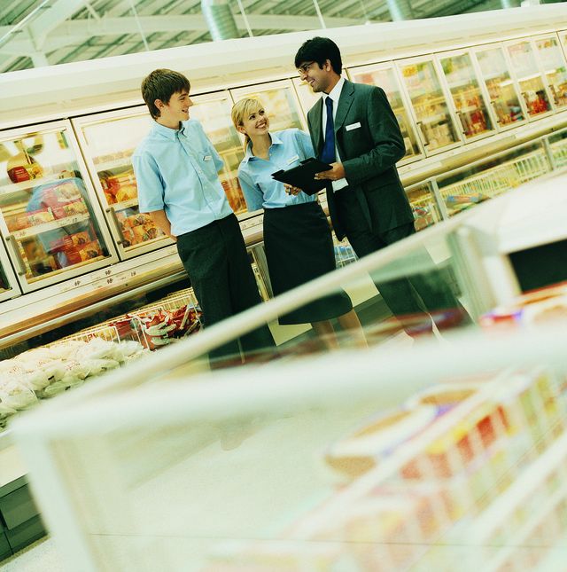 Gérant du magasin d'épicerie parler avec les employés adolescentes