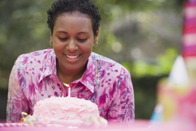 Femme soufflant une bougie de gâteau d'anniversaire.